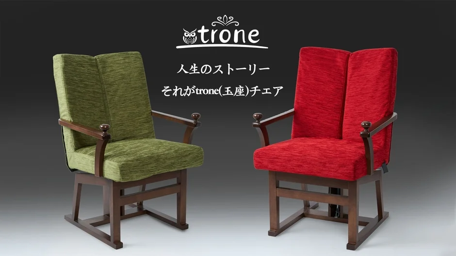 黒い背景に、緑色と赤色の布張りの木製アームチェアが2脚並べられています。