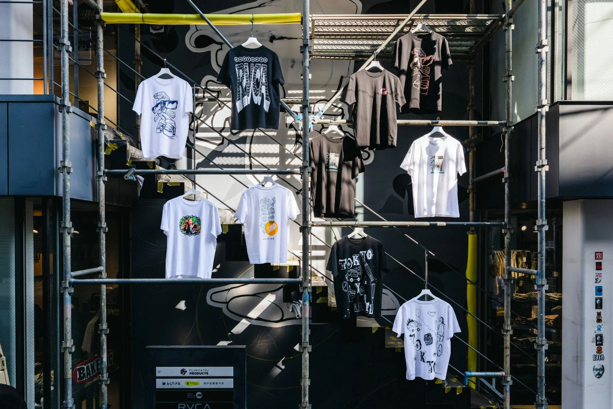 都会の建物の外壁に設置された足場に展示されたTシャツ