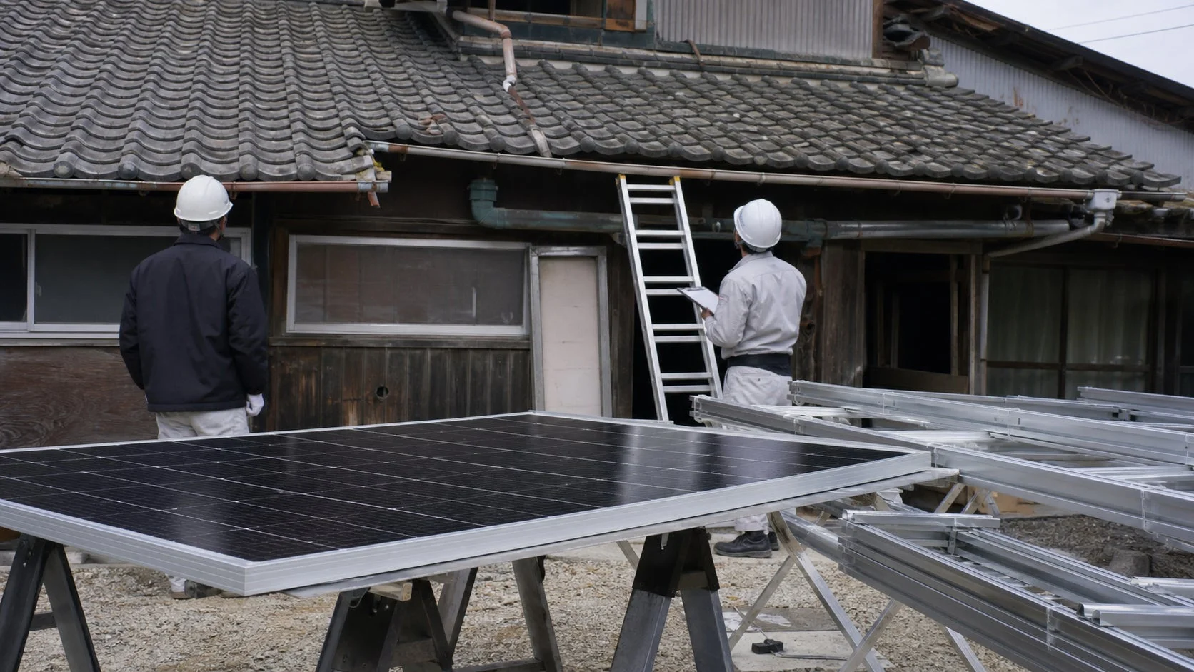 日本家屋の屋根にソーラーパネルを設置準備する作業員