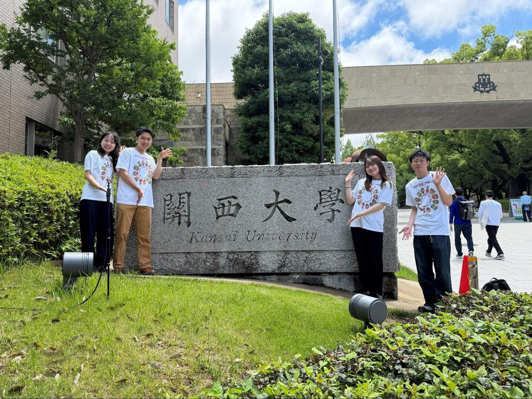 関西大学の石碑前で笑顔の学生たち