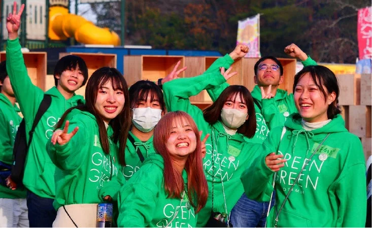 「GREEN GREEN」のパーカーを着た学生グループ