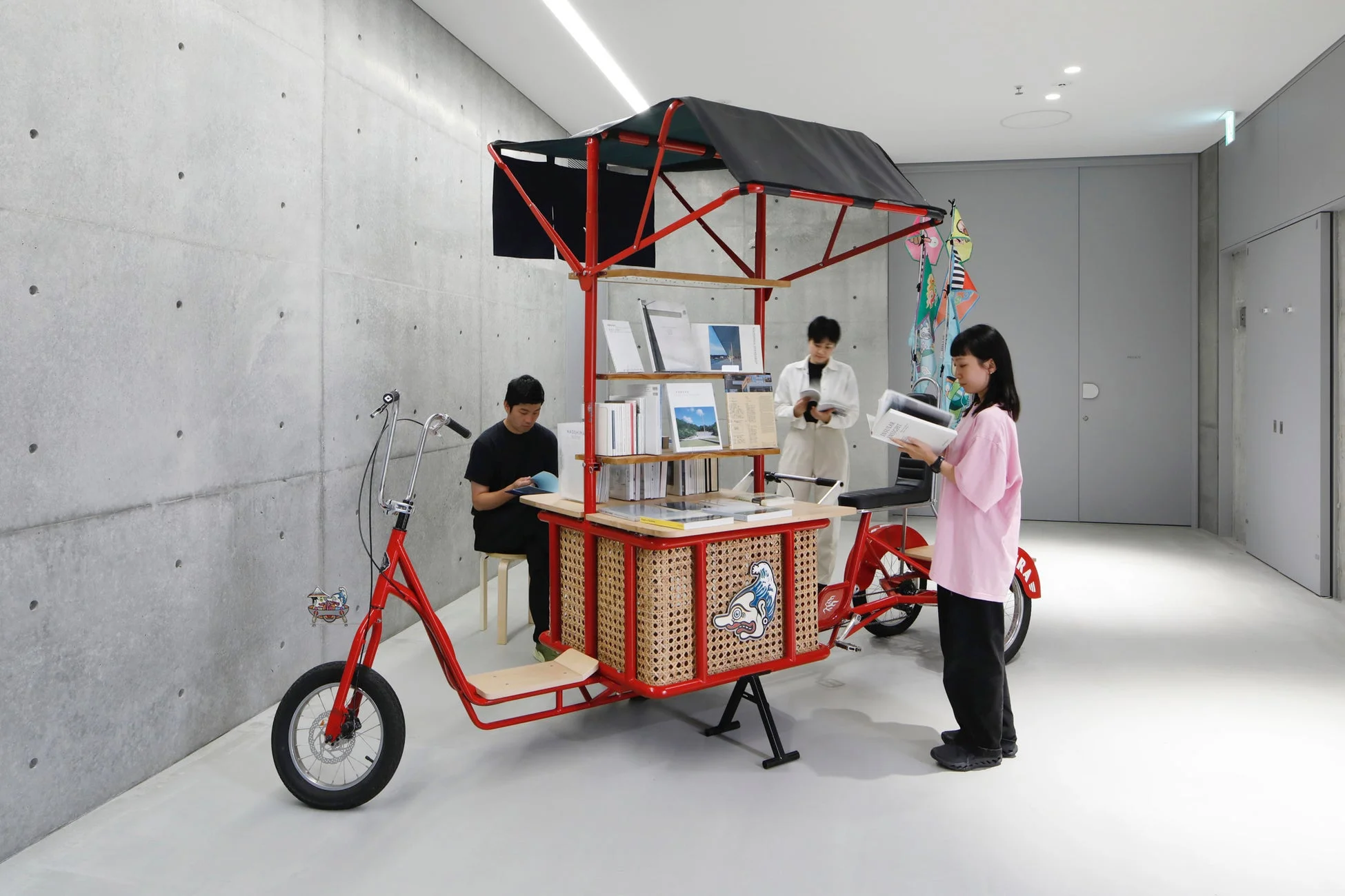 赤い移動式図書館を人々が利用するモダンな屋内空間