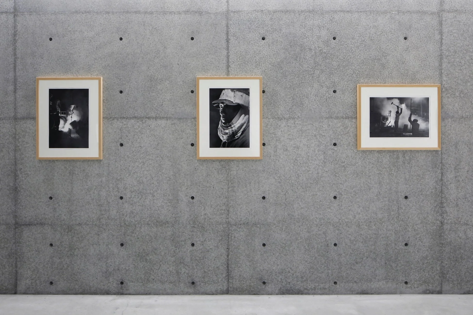 コンクリート壁に展示された工場作業や労働者などのモノクロ写真