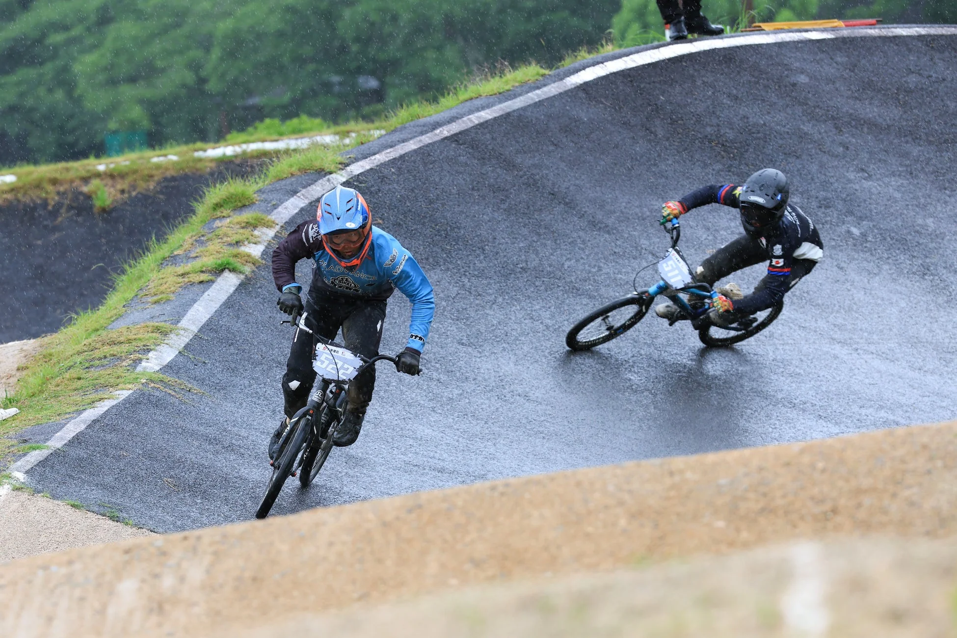 雨の中、BMXレーサーがバンクのあるウェットなトラックを走行