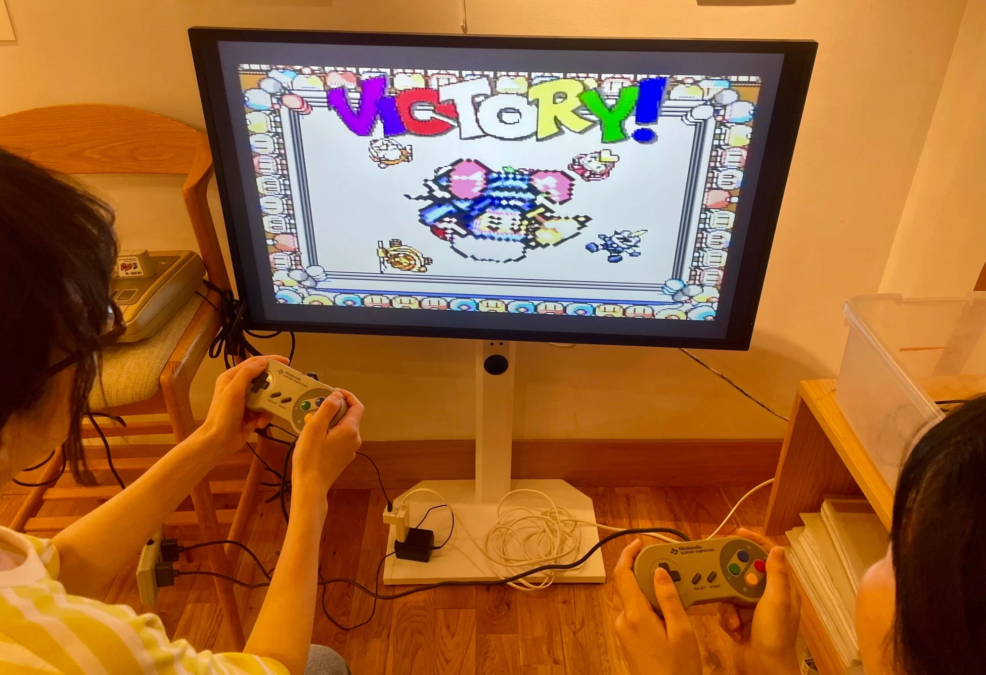 スーパーファミコンでレトロゲームを楽しむ二人の人物