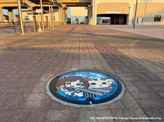 アイドルマスター シンデレラガールズの前川みくがデザインされたマンホール蓋がりんくう常滑駅前の広場に設置されている様子
