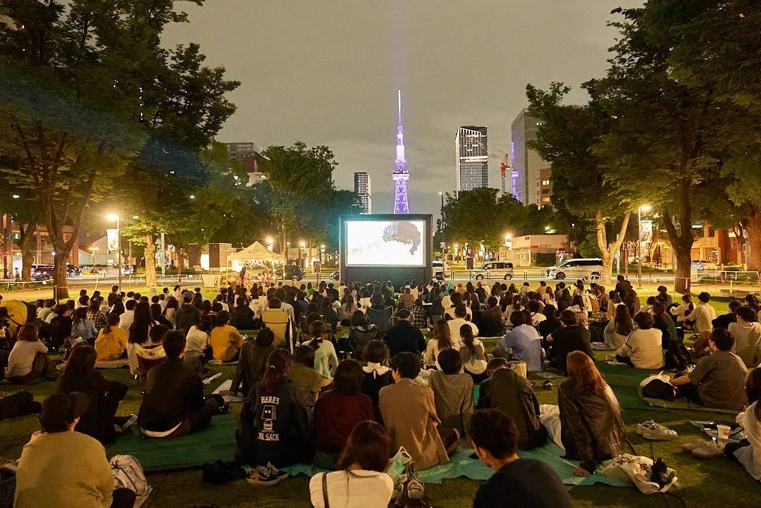 夜の公園で野外映画を楽しむ人々