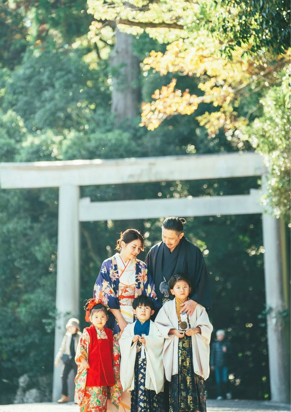 伝統的な和装に身を包んだ家族が、神社の鳥居前で記念撮影をしている様子