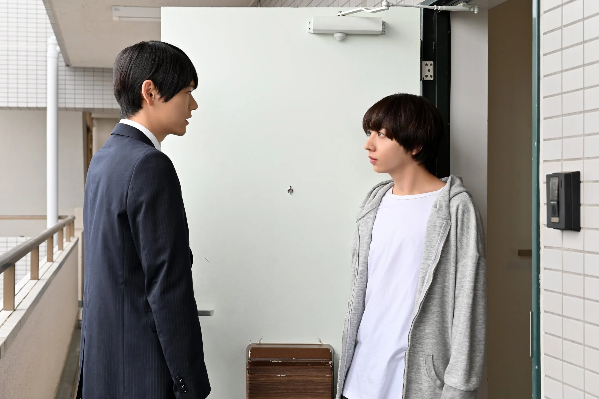 アパートの玄関で向き合う男性二人