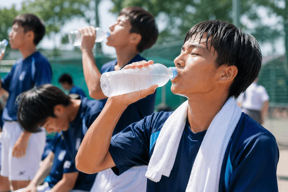 運動後にペットボトルで水分補給をする若者たち