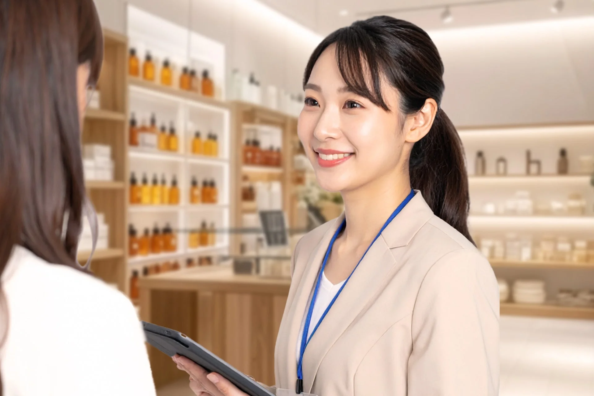店舗で笑顔の女性店員がタブレットを持ち、顧客と対話している様子