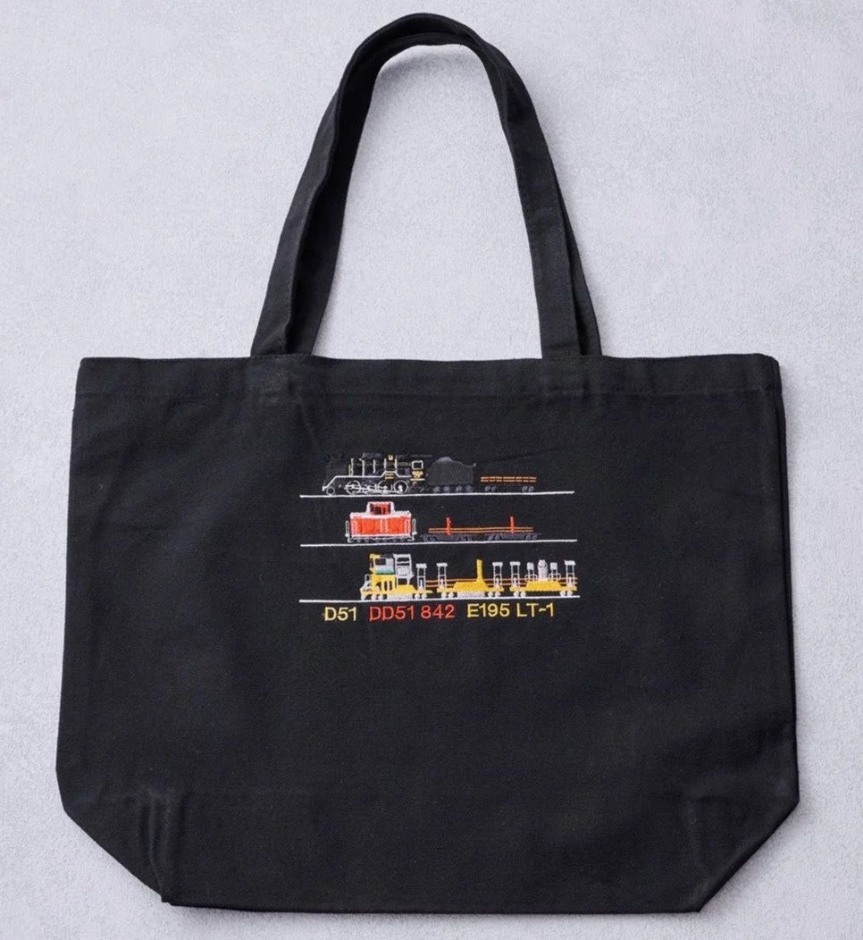 黒いトートバッグに、D51、DD51 842、E195 LT-1などの鉄道車両が刺繍で描かれています