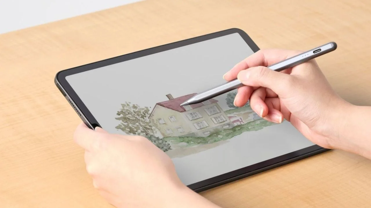 人物がスタイラスペンでタブレットに水彩画風の家と風景を描く様子