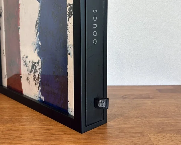 黒い額縁に入った抽象的なアート作品が木製のテーブルに置かれています。