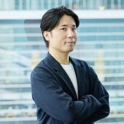 腕を組んでカメラを見つめるアジア系の男性のポートレート