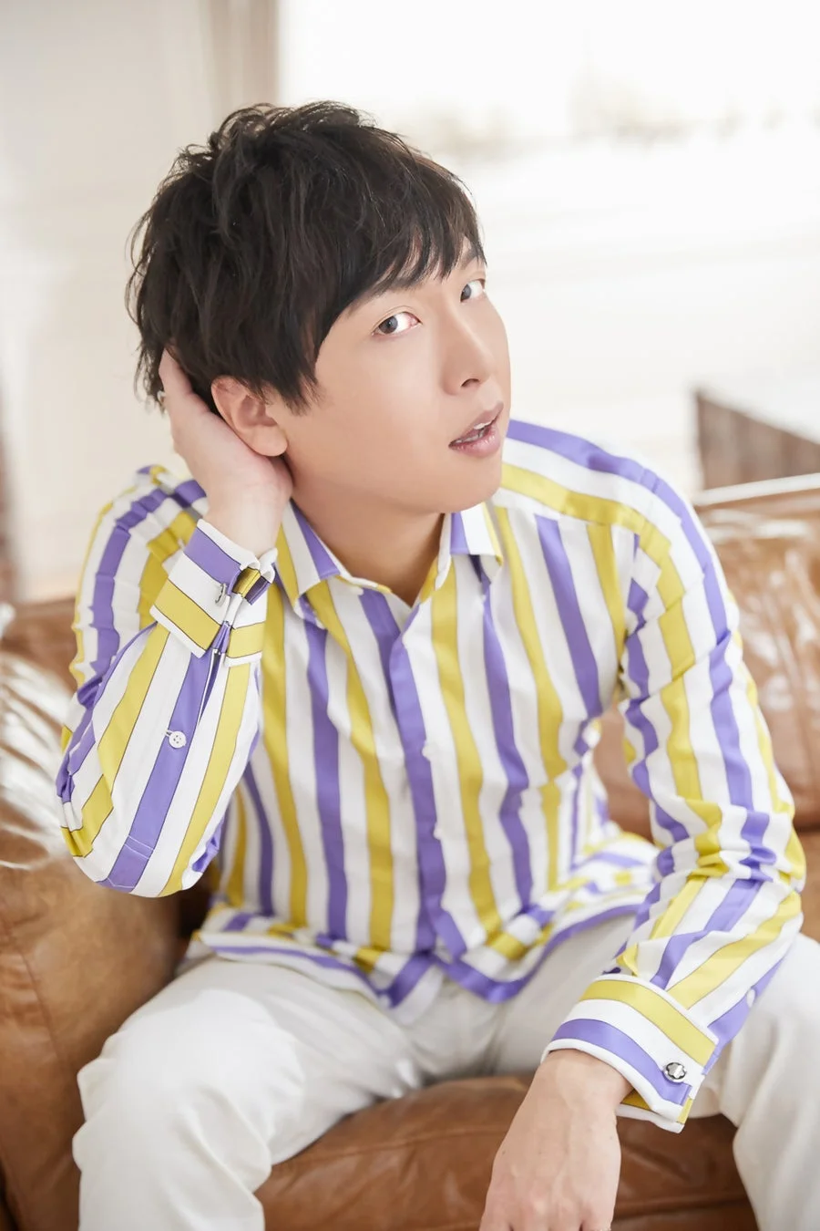 茶色のソファに座った若い男性のポートレート