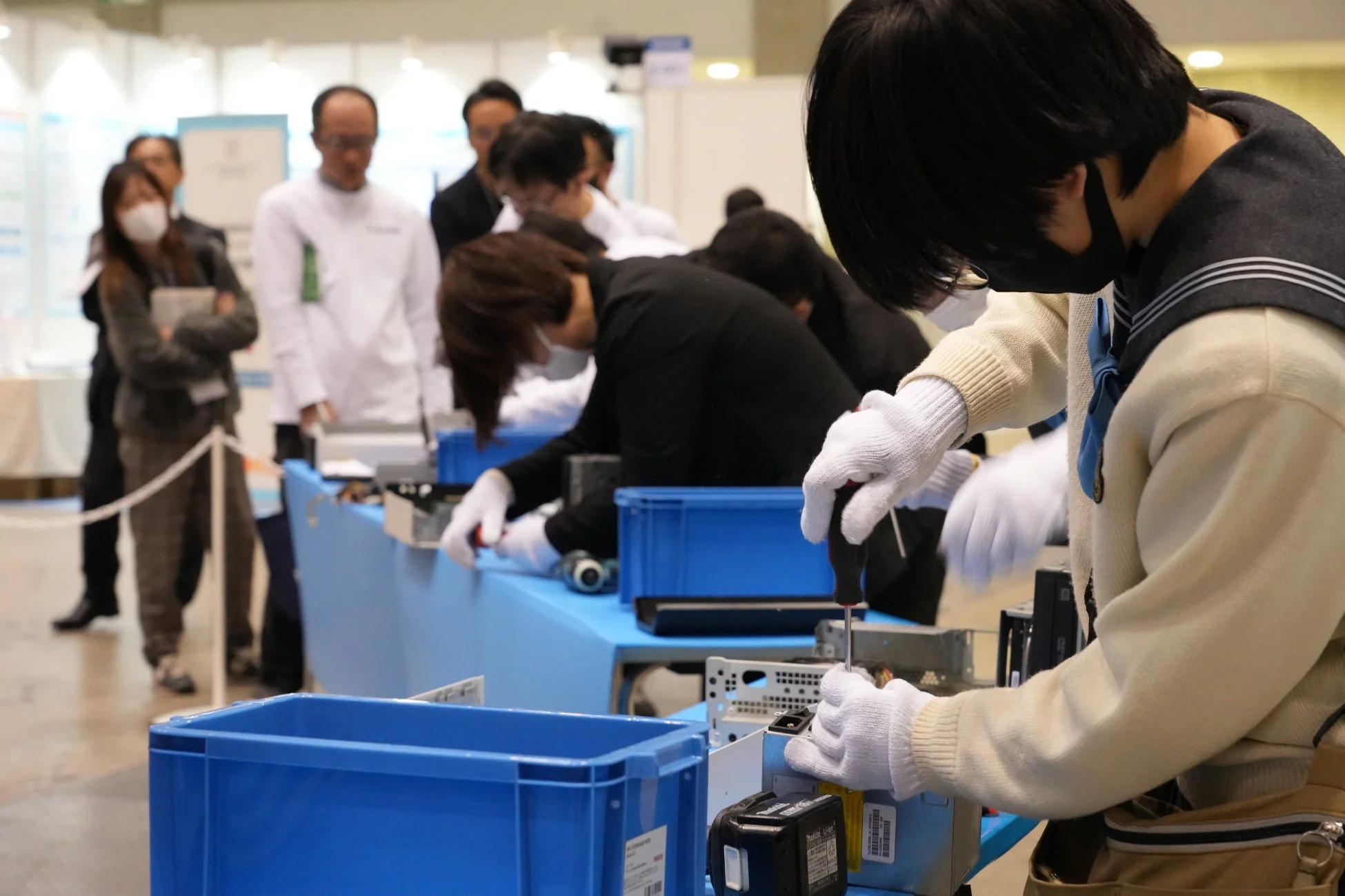 人々が工具を使って電子機器を分解している様子