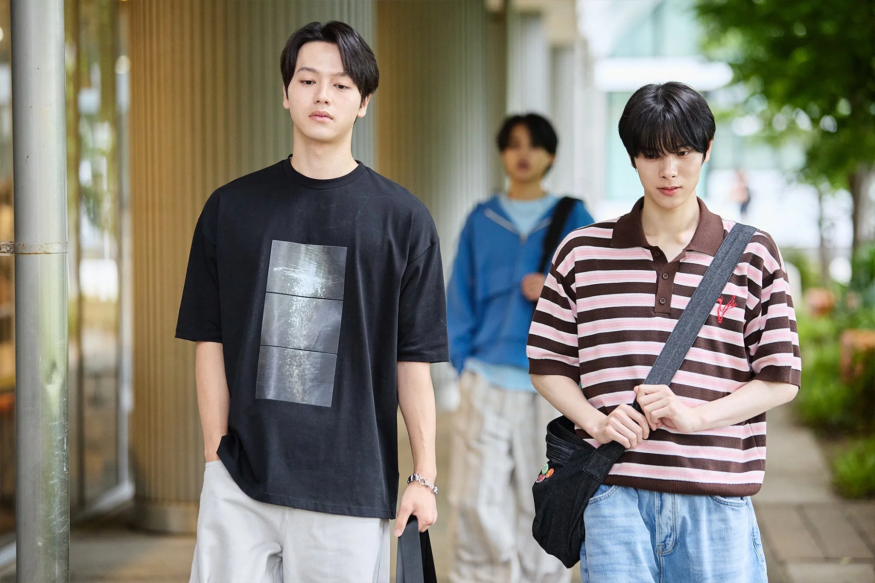 カジュアルな服装の若い男性3人が屋外を歩いている様子。