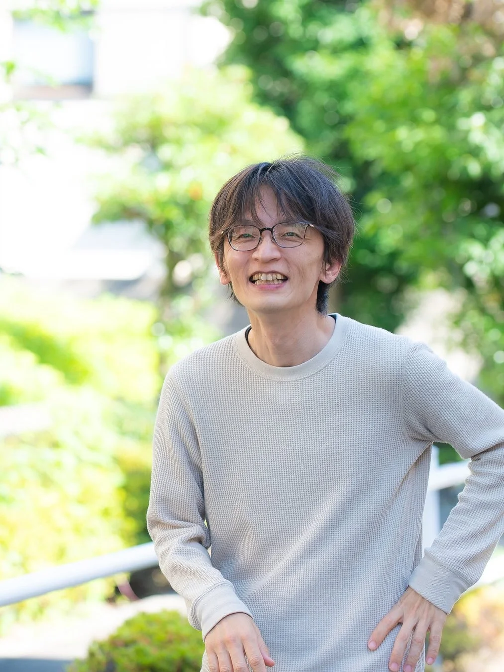 屋外で笑顔を見せるメガネをかけた男性のポートレート