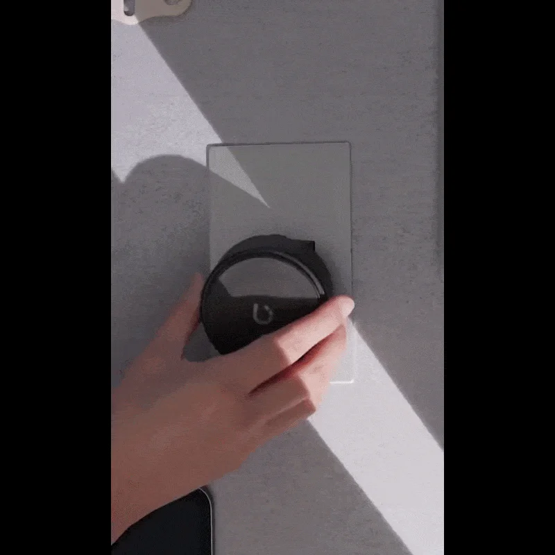 手が壁に取り付けられた黒い丸いスマートデバイスを操作している