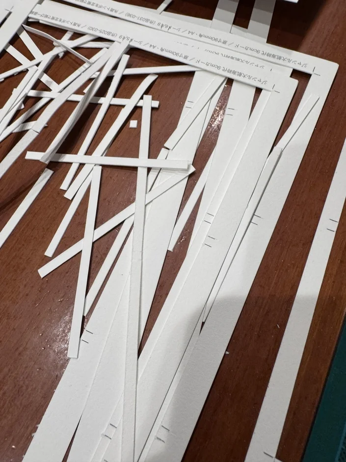 木製のテーブルの上に散らばる白い紙の切れ端