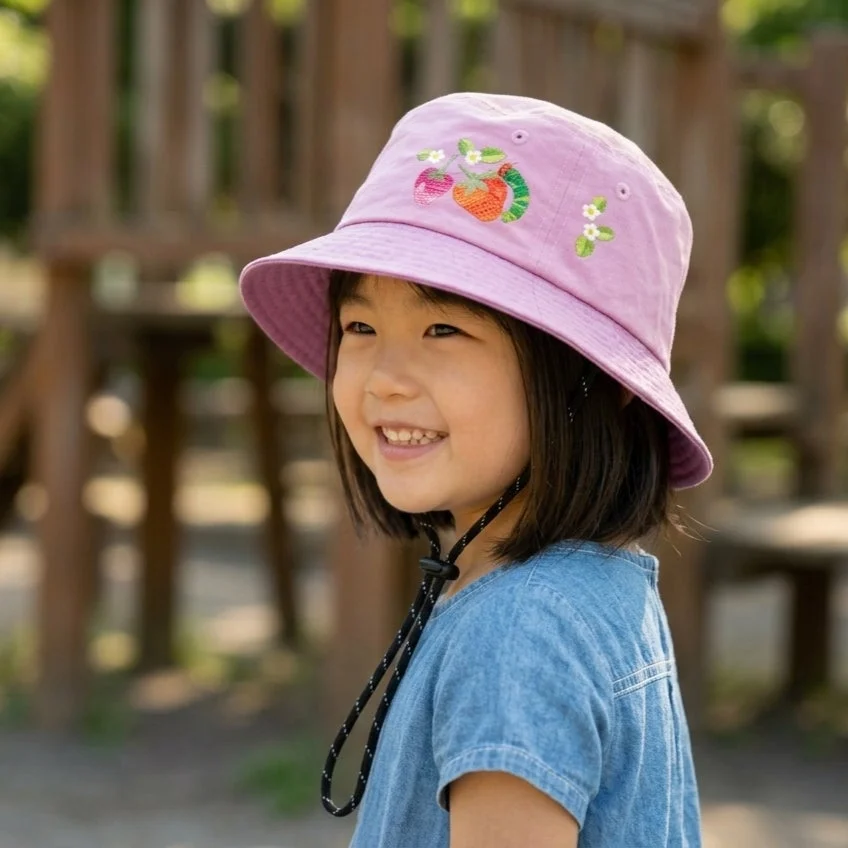紫色のバケットハットをかぶり笑顔の幼い女の子