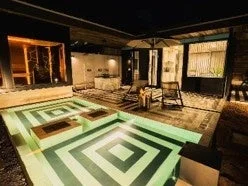 夜にライトアップされた屋外プールとサウナ
