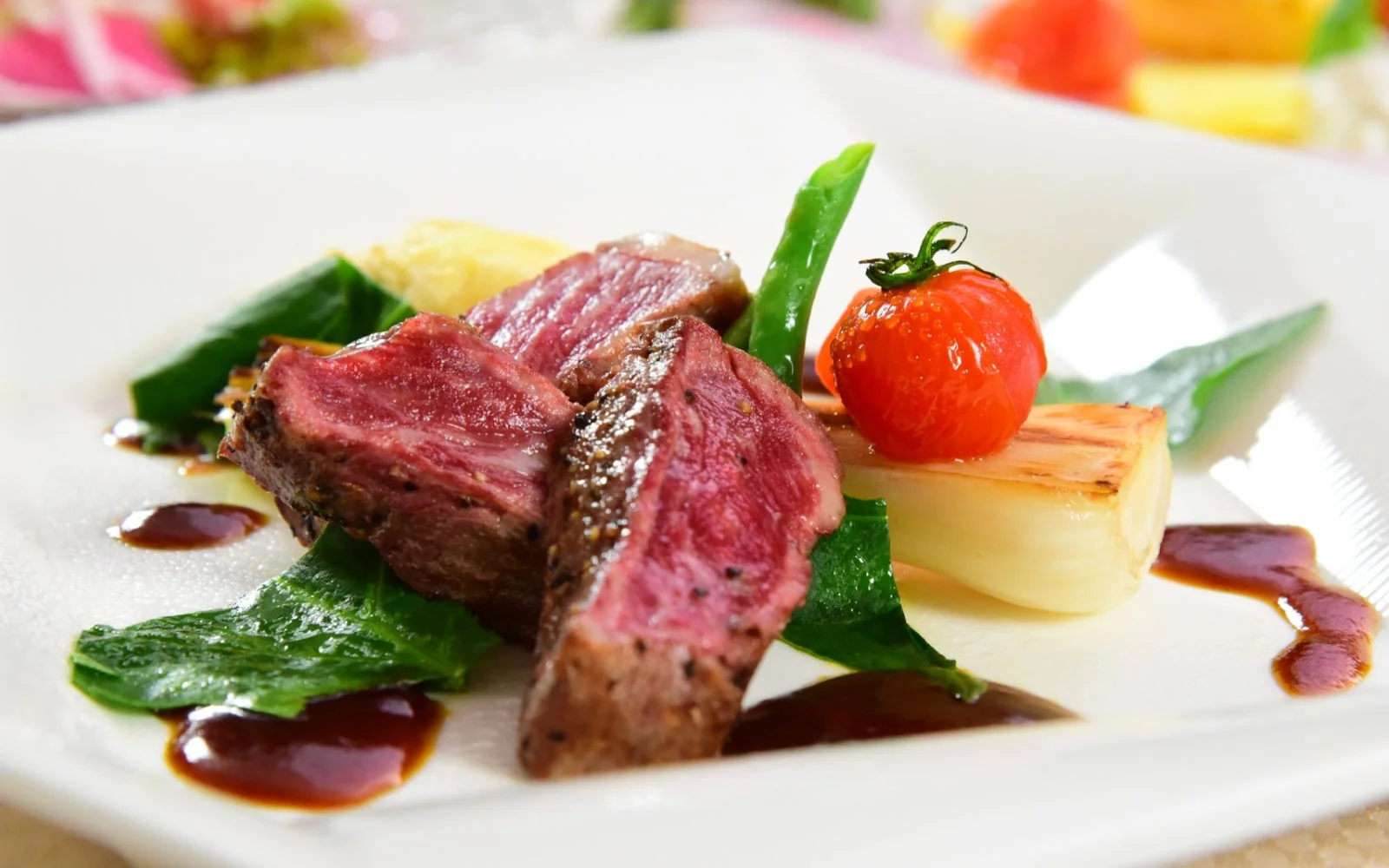 美しく盛り付けられた肉料理で、ミディアムレアの肉が主役