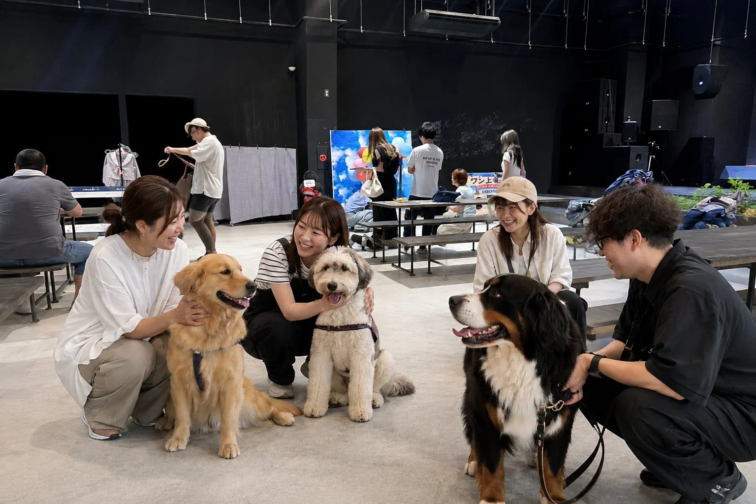 屋内のイベントスペースで、人々が愛犬たちと楽しそうに交流している様子です。